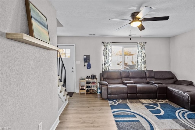 living room with a wealth of natural light, hardwood / wood-style floors, ceiling fan, and a textured ceiling