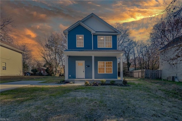 view of front of house featuring a porch, cooling unit, and a lawn