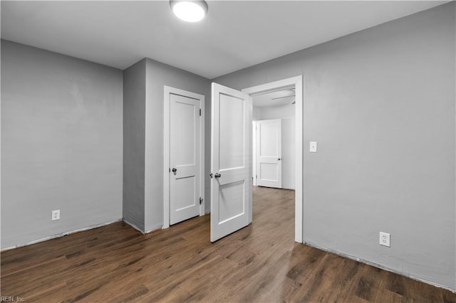 unfurnished bedroom with a closet and dark wood-type flooring