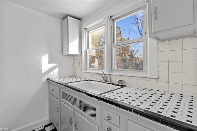 kitchen featuring tile countertops, decorative backsplash, white cabinetry, and sink