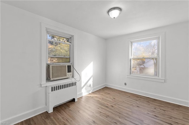 empty room with hardwood / wood-style floors, a wealth of natural light, and radiator