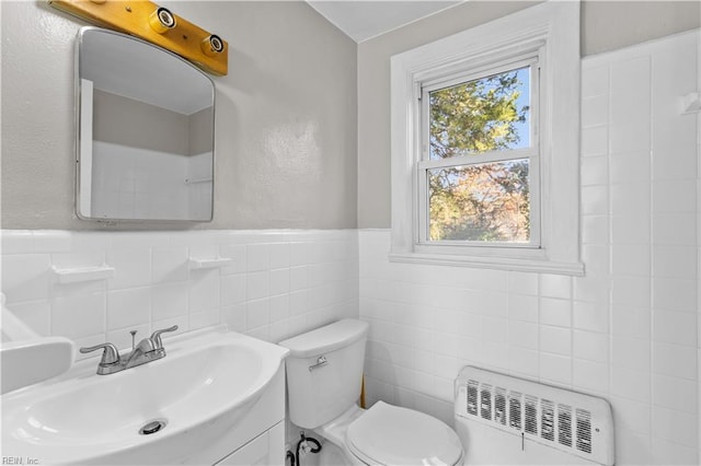 bathroom featuring vanity, toilet, radiator, and tile walls