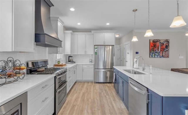 kitchen featuring white cabinetry, wall chimney range hood, sink, and appliances with stainless steel finishes