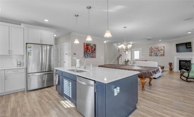 kitchen with stainless steel appliances, blue cabinets, sink, decorative light fixtures, and white cabinets