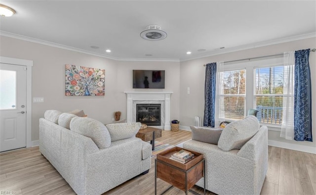 living room featuring a high end fireplace, light hardwood / wood-style floors, plenty of natural light, and crown molding