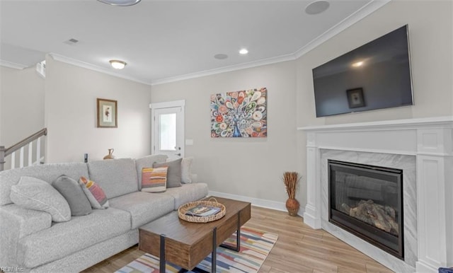 living room featuring light hardwood / wood-style floors, crown molding, and a premium fireplace