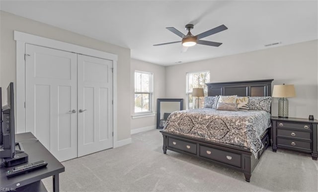 bedroom with ceiling fan, a closet, and light colored carpet