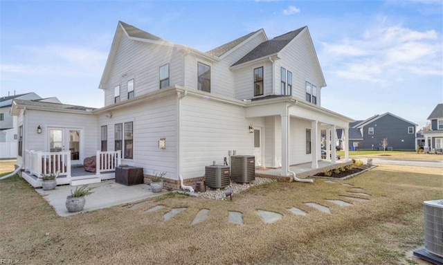 view of side of home featuring central air condition unit, a yard, covered porch, and french doors