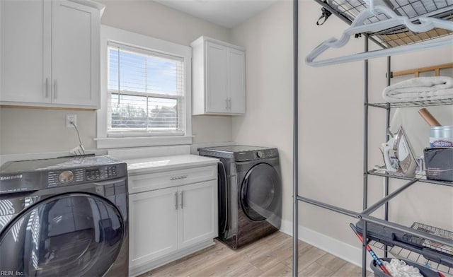 laundry room featuring light hardwood / wood-style floors, cabinets, and washing machine and clothes dryer