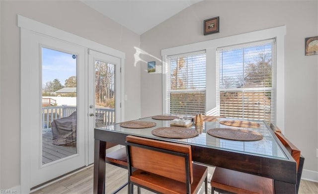 dining space with lofted ceiling, light wood-type flooring, and a healthy amount of sunlight