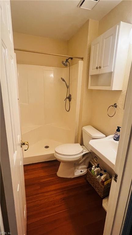 bathroom featuring a shower, toilet, and hardwood / wood-style flooring