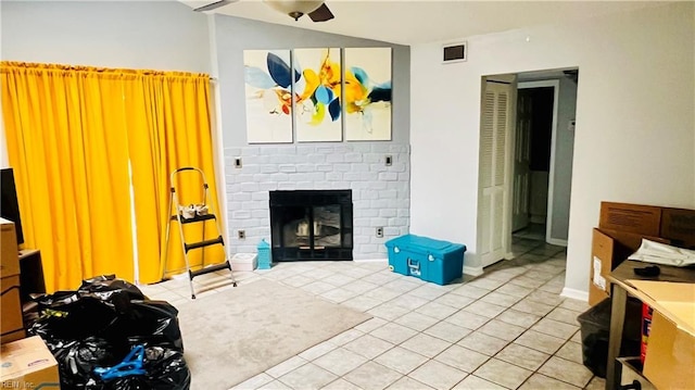 living room with ceiling fan, vaulted ceiling, light tile patterned floors, and a brick fireplace