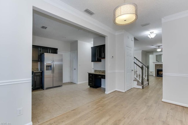 kitchen featuring light wood-type flooring, stainless steel refrigerator with ice dispenser, and a textured ceiling