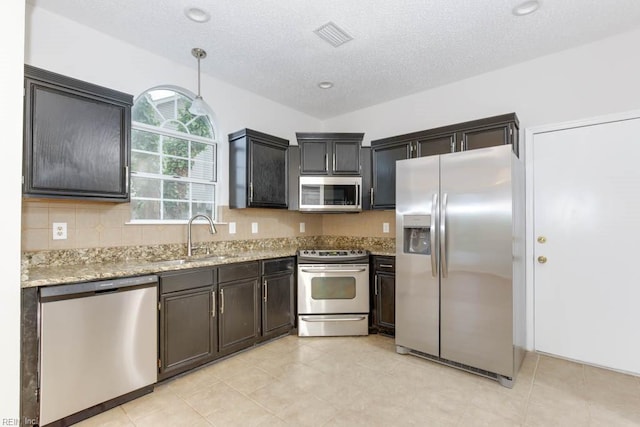 kitchen featuring hanging light fixtures, sink, light stone countertops, a textured ceiling, and appliances with stainless steel finishes