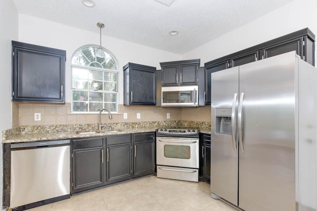 kitchen featuring light stone countertops, hanging light fixtures, a textured ceiling, decorative backsplash, and appliances with stainless steel finishes