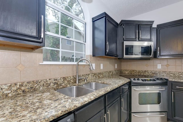 kitchen featuring light stone countertops, sink, stainless steel appliances, backsplash, and a textured ceiling