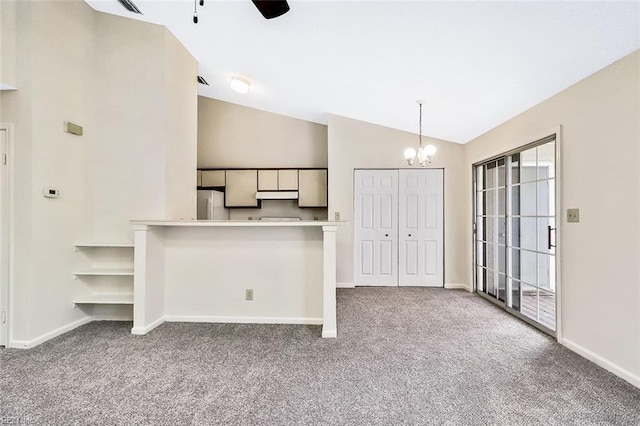 unfurnished living room with ceiling fan with notable chandelier, carpet floors, and lofted ceiling