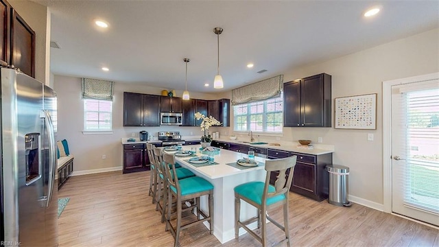 kitchen with dark brown cabinets, stainless steel appliances, and hanging light fixtures