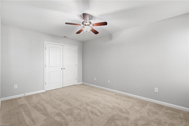 unfurnished bedroom featuring light carpet, a closet, and ceiling fan