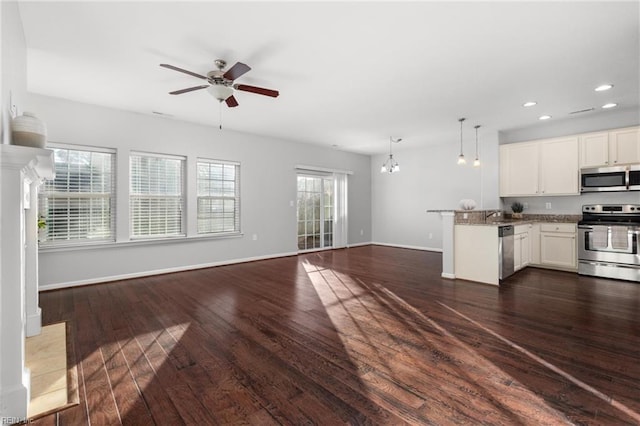 kitchen featuring white cabinets, decorative light fixtures, dark hardwood / wood-style flooring, kitchen peninsula, and stainless steel appliances