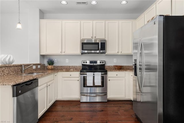 kitchen with stainless steel appliances, sink, stone countertops, dark hardwood / wood-style floors, and hanging light fixtures