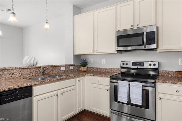 kitchen with dark hardwood / wood-style flooring, stainless steel appliances, sink, white cabinets, and hanging light fixtures