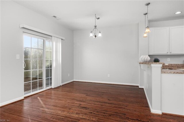 unfurnished dining area with dark wood-type flooring and an inviting chandelier