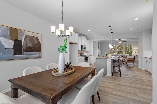 dining area with ceiling fan with notable chandelier and light wood-type flooring