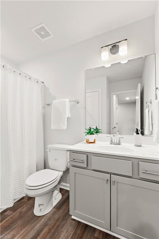 bathroom featuring a shower with shower curtain, wood-type flooring, vanity, and toilet