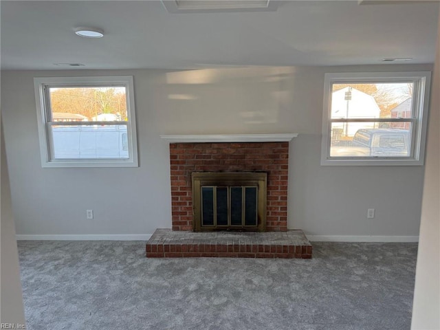 unfurnished living room with carpet flooring, a brick fireplace, and a wealth of natural light