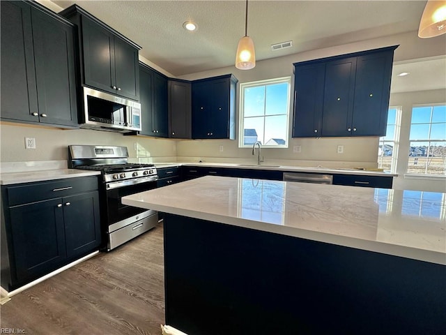 kitchen featuring a healthy amount of sunlight, appliances with stainless steel finishes, sink, and hanging light fixtures