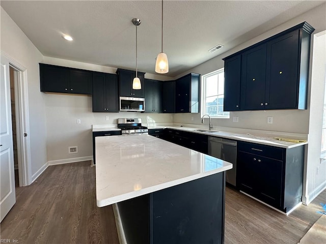 kitchen featuring hanging light fixtures, a kitchen island, wood-type flooring, and appliances with stainless steel finishes