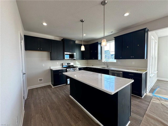 kitchen featuring sink, stainless steel appliances, dark hardwood / wood-style floors, a center island, and decorative light fixtures