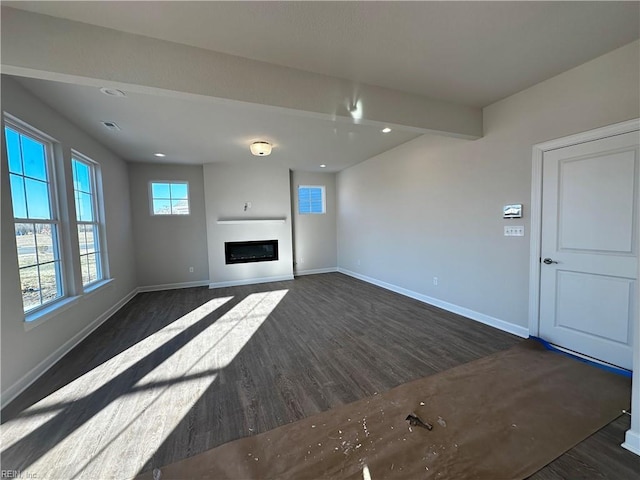 unfurnished living room featuring dark wood-type flooring and beam ceiling