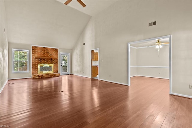 unfurnished living room with hardwood / wood-style floors, plenty of natural light, a fireplace, and high vaulted ceiling