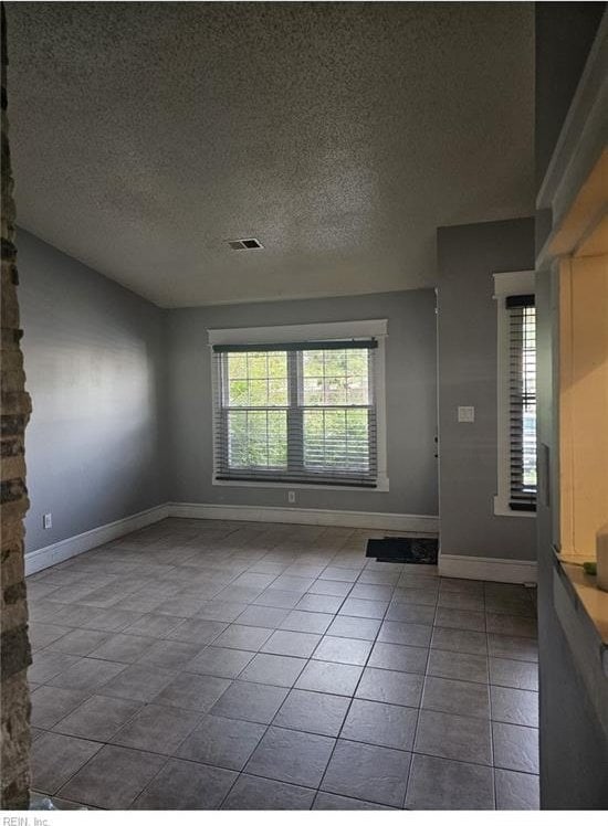 unfurnished room featuring a textured ceiling and tile patterned floors