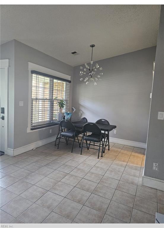 tiled dining room featuring a textured ceiling and a notable chandelier