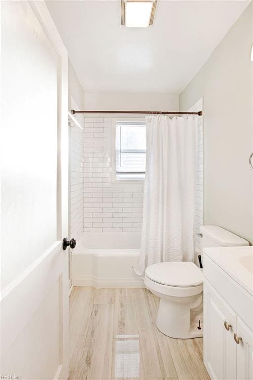 full bathroom with hardwood / wood-style flooring, vanity, shower / bath combination with curtain, and toilet