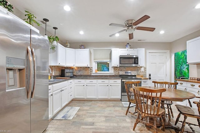 kitchen with stainless steel appliances, ceiling fan, sink, white cabinets, and light hardwood / wood-style floors