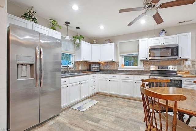 kitchen with sink, stainless steel appliances, light hardwood / wood-style flooring, decorative backsplash, and white cabinets