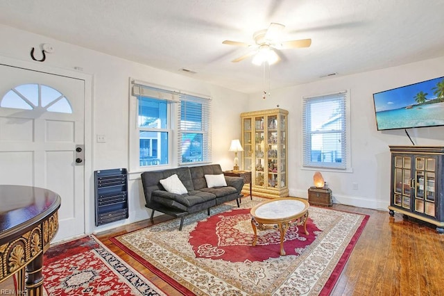 living room featuring hardwood / wood-style flooring, ceiling fan, and heating unit