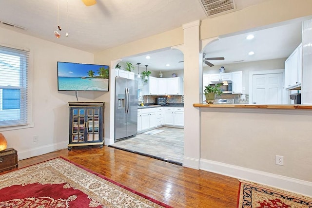 kitchen with hardwood / wood-style flooring, backsplash, white cabinets, and stainless steel appliances