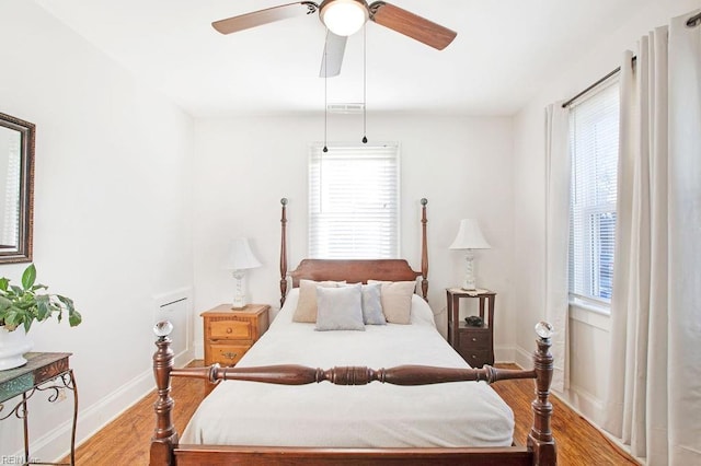 bedroom with ceiling fan, light hardwood / wood-style floors, and multiple windows