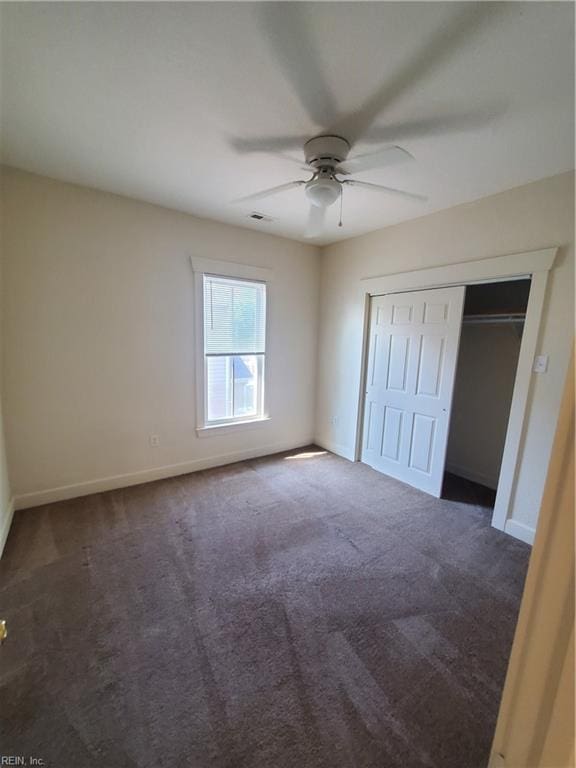 unfurnished bedroom featuring a closet, dark carpet, and ceiling fan