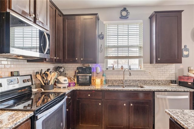 kitchen featuring light stone countertops, appliances with stainless steel finishes, tasteful backsplash, and sink