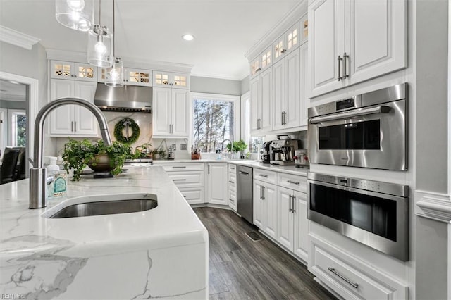 kitchen with white cabinets, stainless steel appliances, decorative light fixtures, and ornamental molding