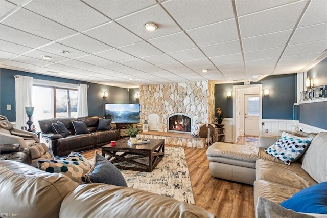 living room with hardwood / wood-style floors, a paneled ceiling, and a stone fireplace