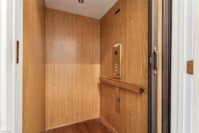 details with hardwood / wood-style floors, elevator, and wooden walls