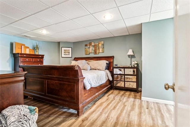 bedroom with a drop ceiling and hardwood / wood-style flooring