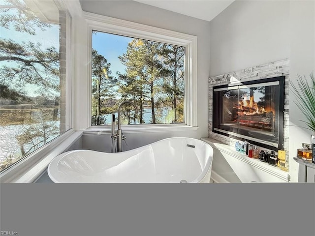 bathroom with plenty of natural light, a multi sided fireplace, and a bath